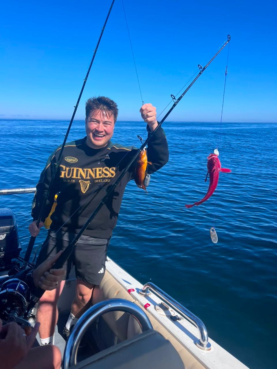 A guest holding up two freshly caught reef fish on the boat